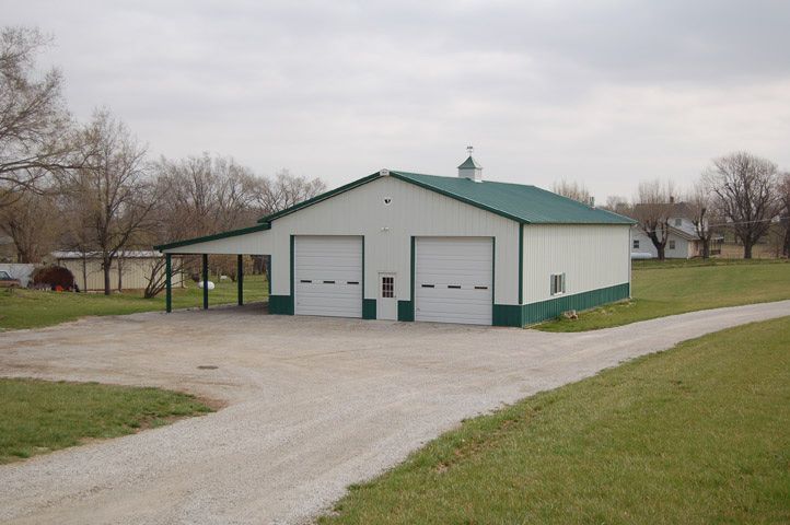 A white garage with a green roof and white doors